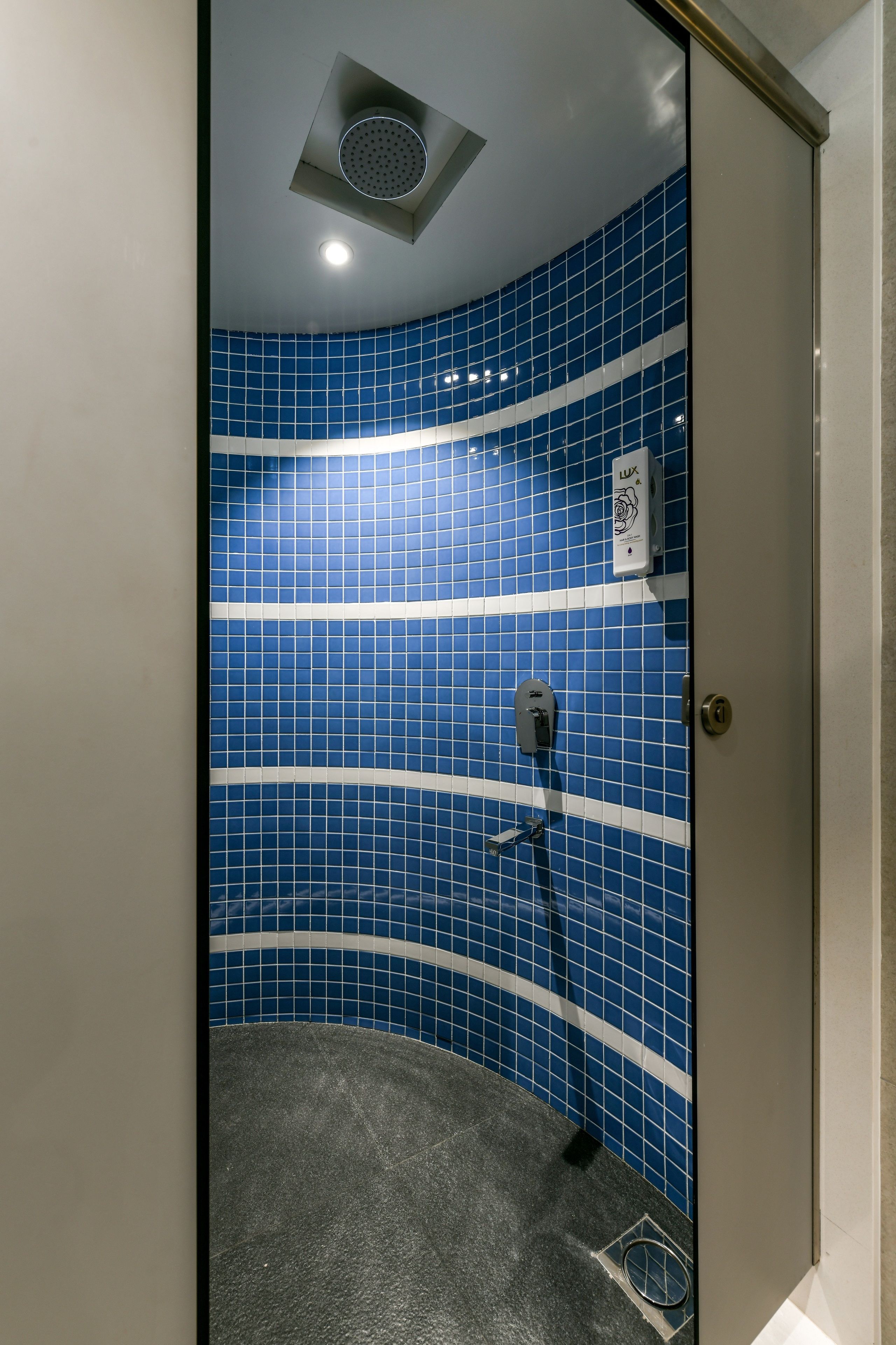 A shower with blue tiles and a handheld showerhead.