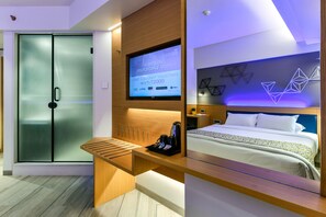 A modern hotel room with a bed, a desk with a coffee maker, a TV displaying a registration screen, and a sliding door. - Indie Stays -BKC, Kalina (Mumbai)