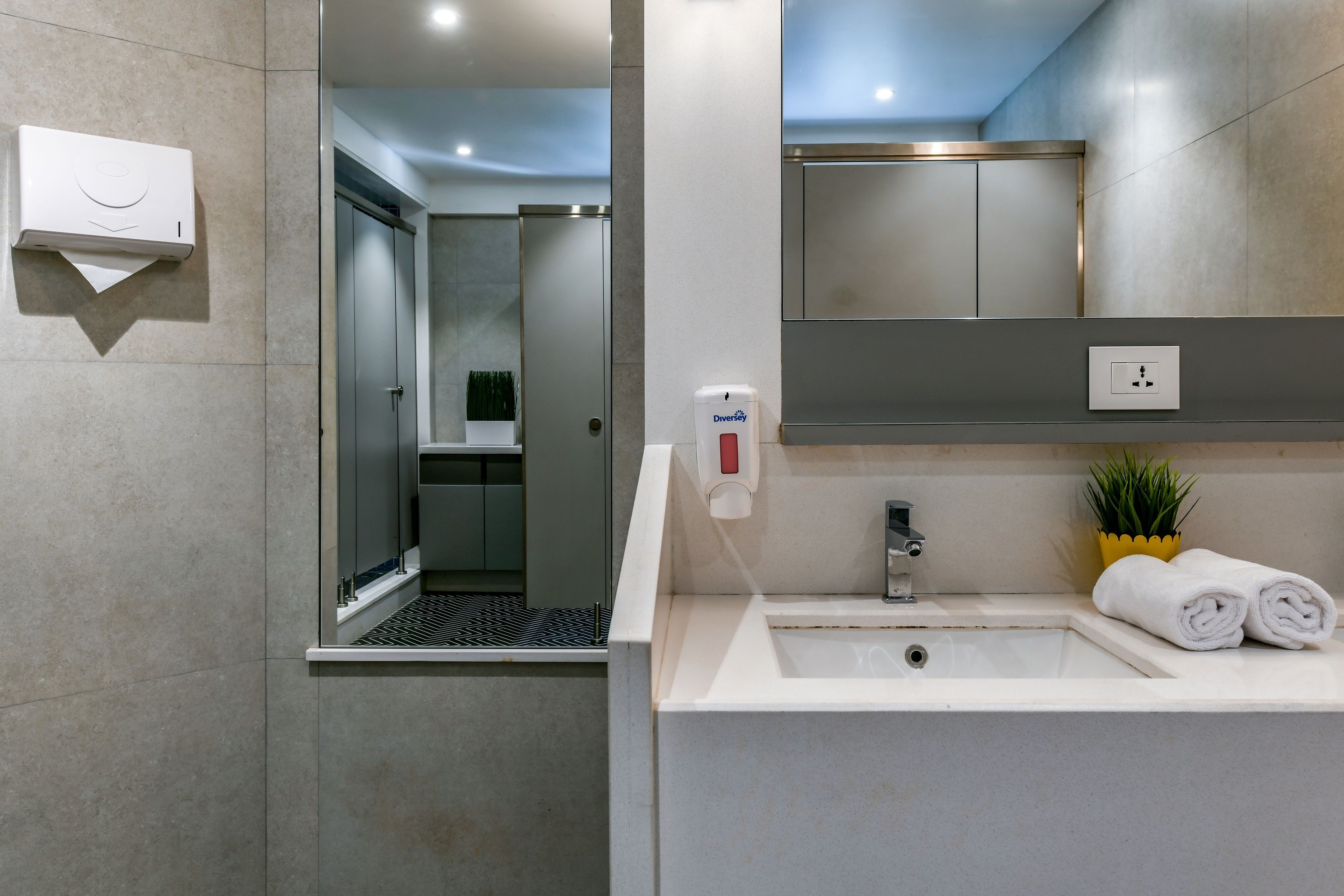 A modern bathroom with a sink, mirror, and a shower area.