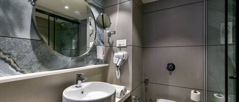 A modern bathroom with a large mirror, a sink, a toilet, and a glass shower enclosure.
