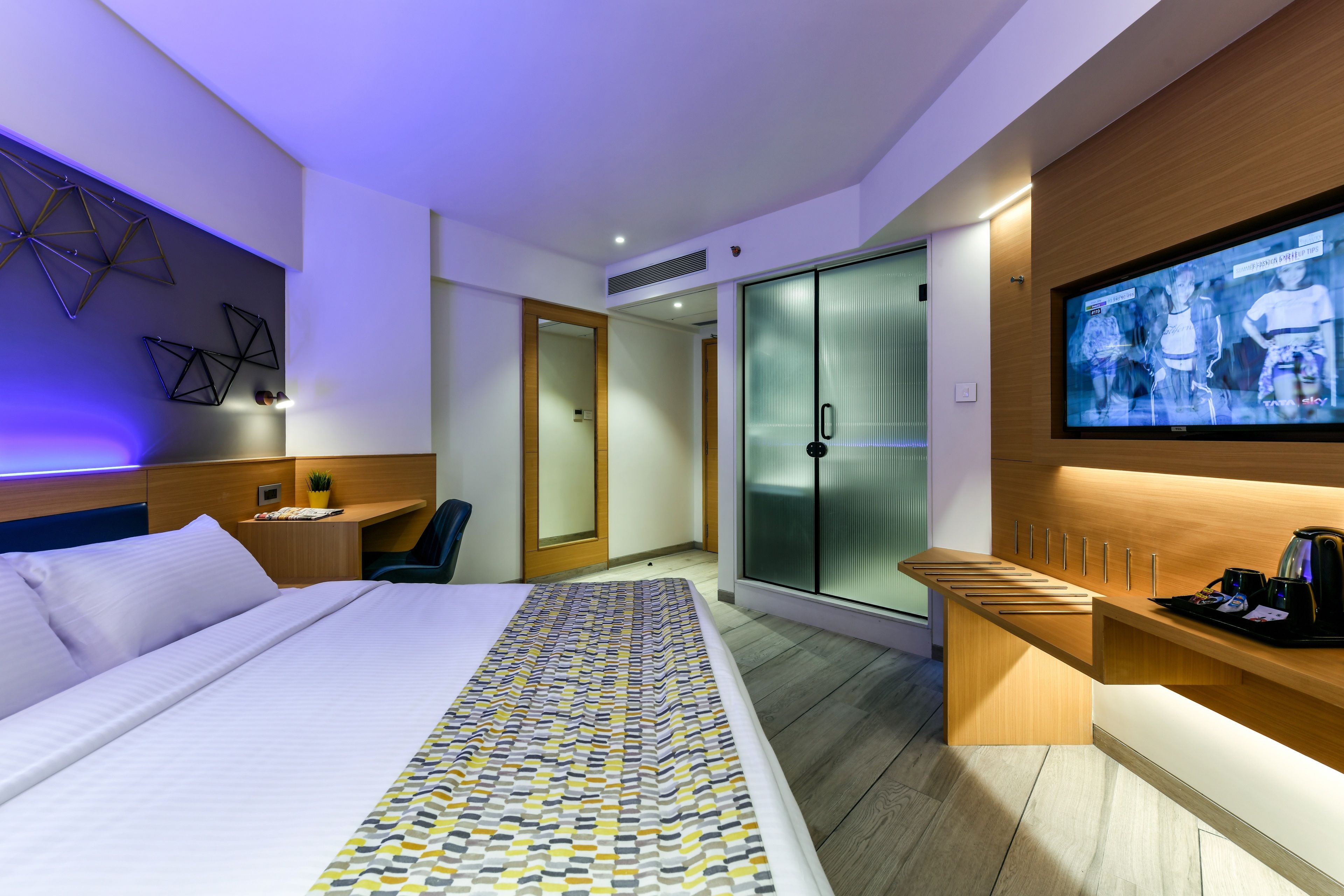 Habitació d'hotel moderna amb un llit gran, escriptori, televisió i armari.