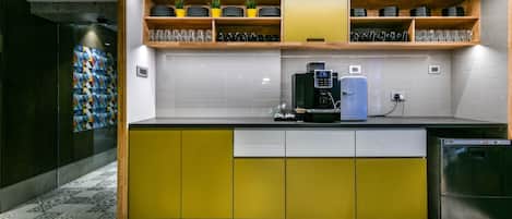 Una cocina moderna con gabinetes amarillos, una cafetera y un refrigerador.