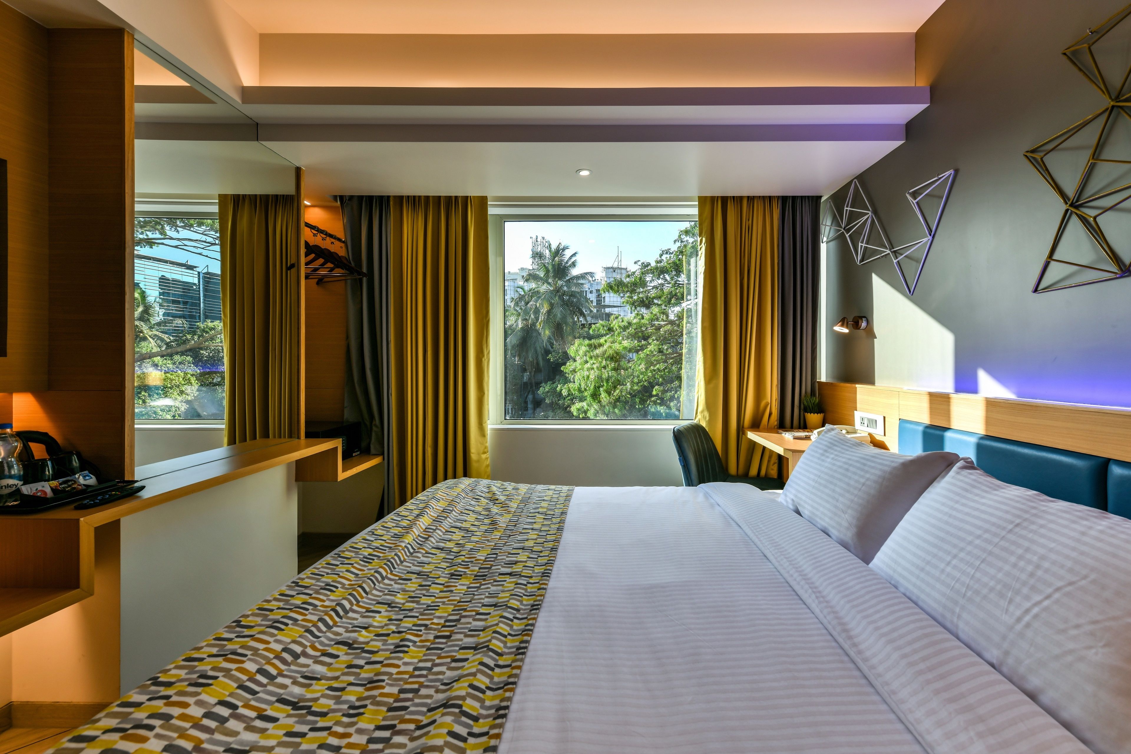 A hotel room with a bed, a desk, and a window with curtains.