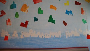 A wall with colorful paper cutouts of buildings and shapes. - B&B Isole (Naples)
