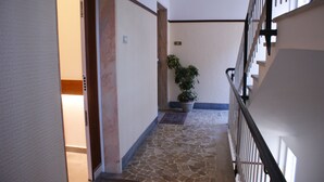 A hallway with a tiled floor, a potted plant, and a door with a light switch. - B&B Isole (Naples)