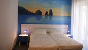 A bedroom with a bed, two bedside tables, and a painting of a coastal scene on the wall. - B&B Isole (Naples)