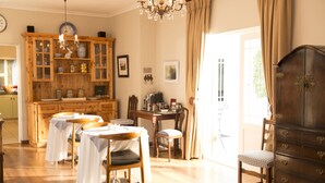 Un espace repas avec des tables et des chaises en bois, un lustre et un buffet en bois doté de portes en verre.