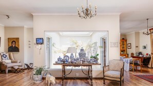 Un salon doté d'un parquet en bois, d'une table ornée d'objets décoratifs, d'un canapé, d'un fauteuil et d'un lustre.
