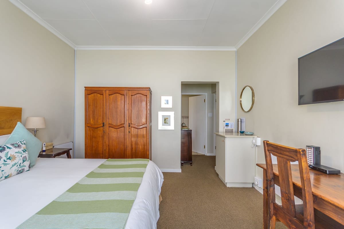 A hotel room with a bed, a desk, a wardrobe, and a television.