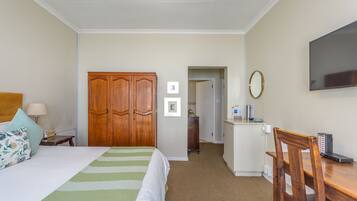 A hotel room with a bed, a desk, a wardrobe, and a television.