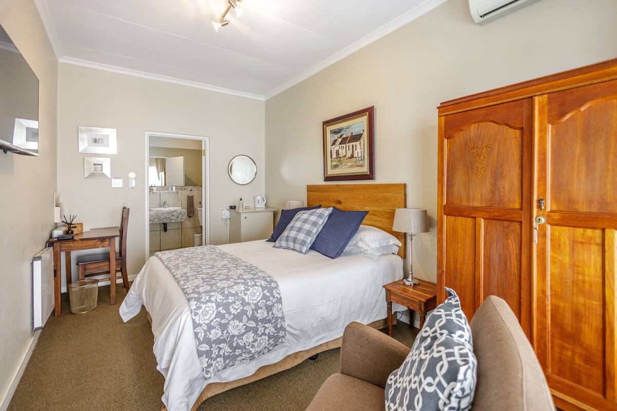 A hotel room with a bed, a desk, a chair, a wardrobe, and a bathroom.
