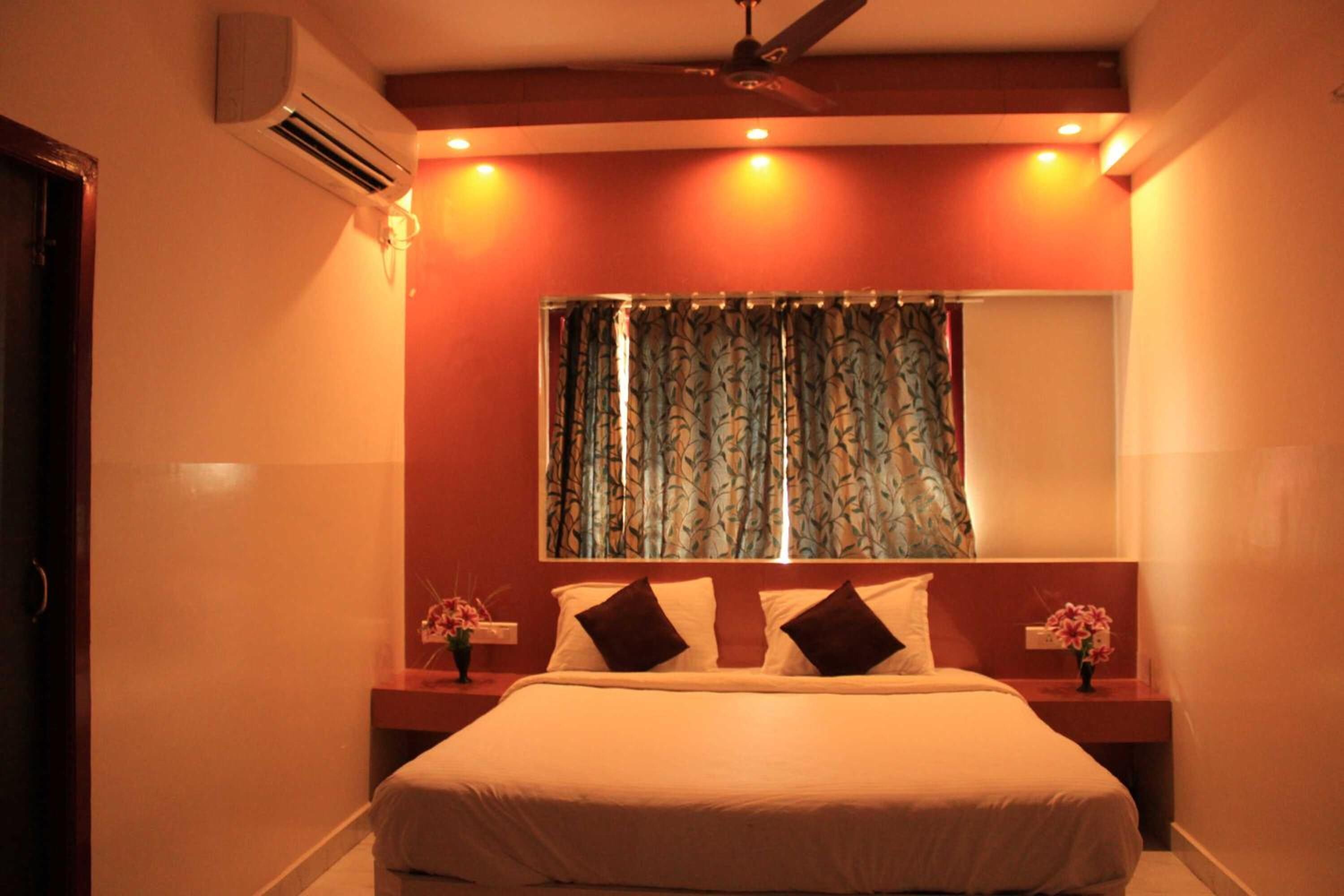 A bedroom with a bed, nightstands, a mirror, and a window with curtains.