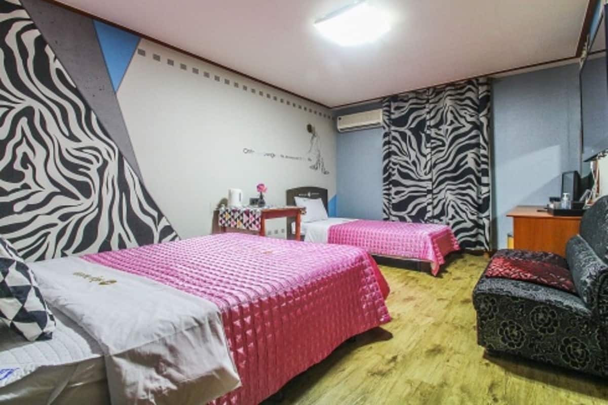 A room with two beds, a sofa, zebra-patterned wallpaper, and a ceiling light.