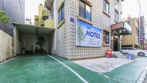 Un hotel con un cartel que dice "SKY HOTEL" y una zona de estacionamiento techada.