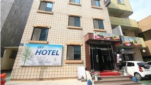 Un hotel con fachada de baldosas, varias ventanas y un cartel anunciando el hotel.