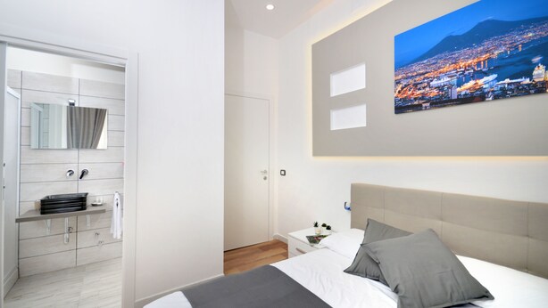 Un dormitorio moderno con una cama grande, una mesita de noche, un armario empotrado y vistas a la ciudad.
