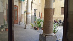 Un patio con columnas, plantas en macetas y una motocicleta al fondo.