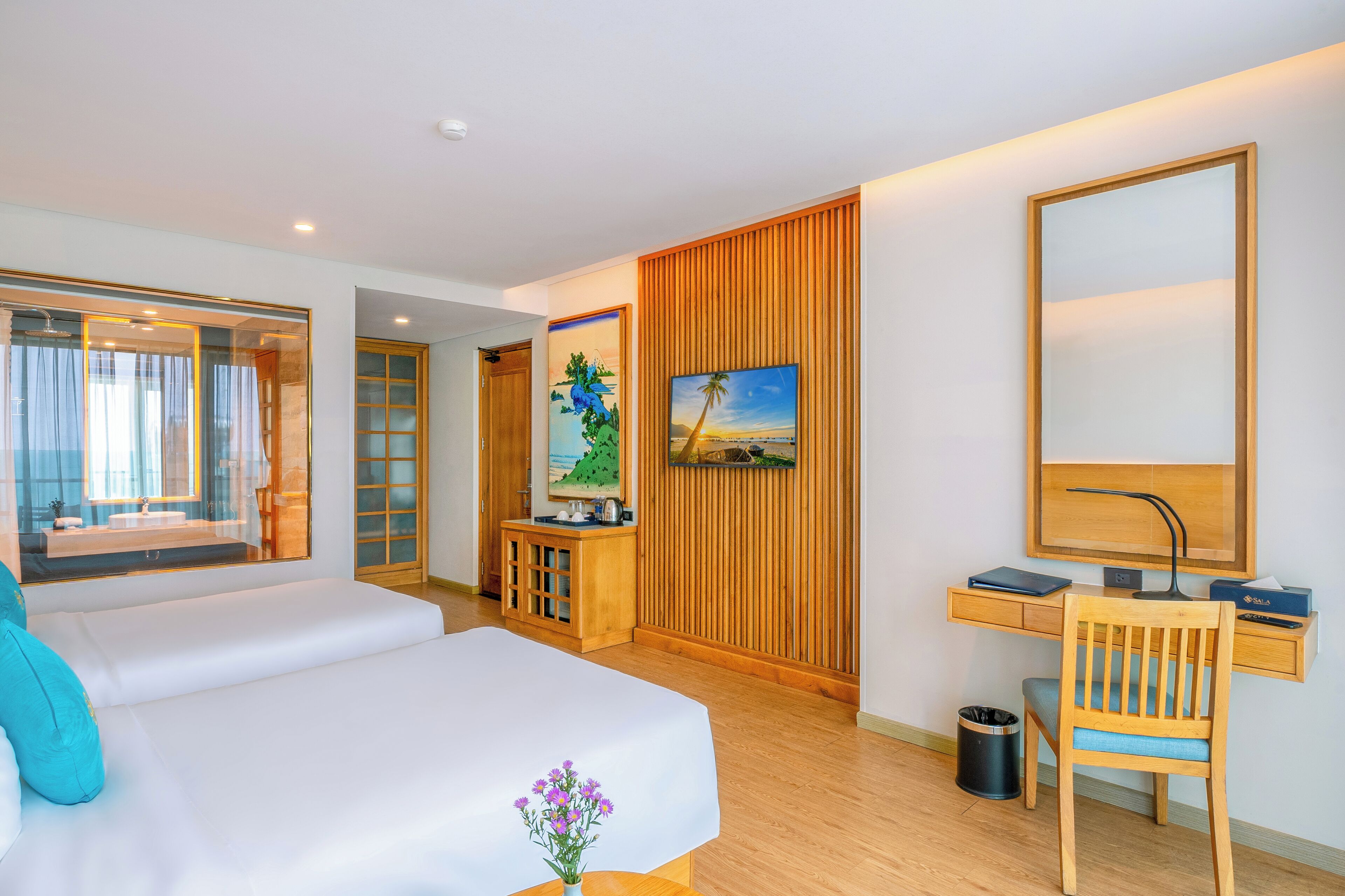A hotel room with a bed, a desk, a chair, a TV, and a window with curtains.