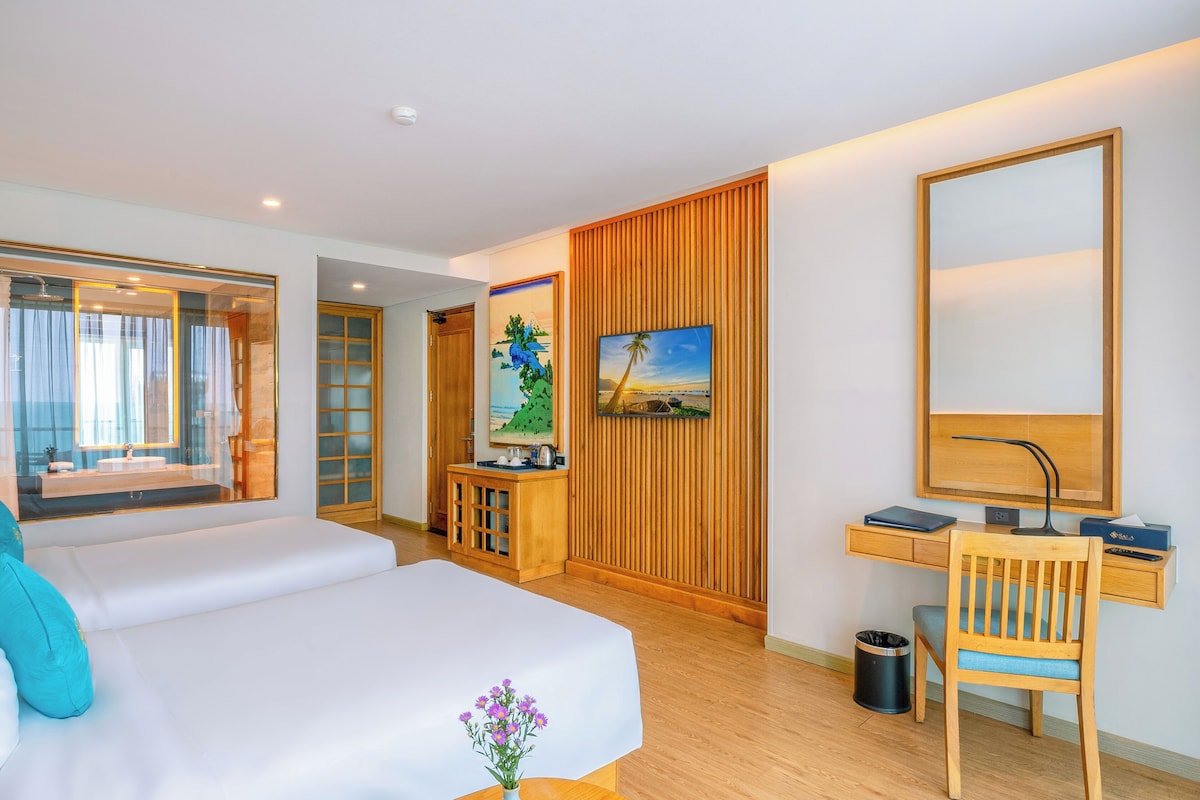 A hotel room with a bed, a desk, a chair, a TV, and a window with curtains.