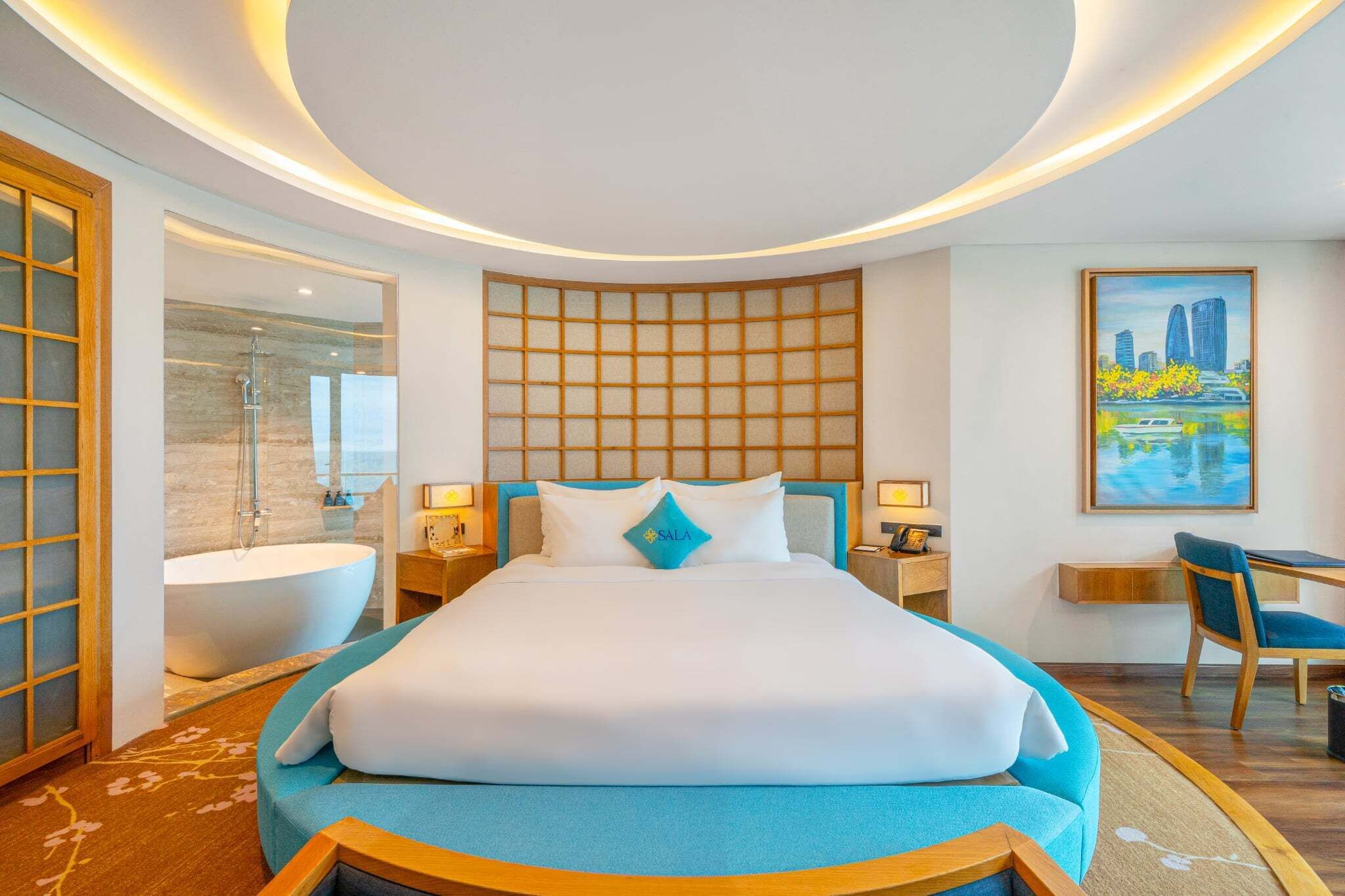 A modern hotel room with a large bed, a bathtub, a desk, and a cityscape painting.