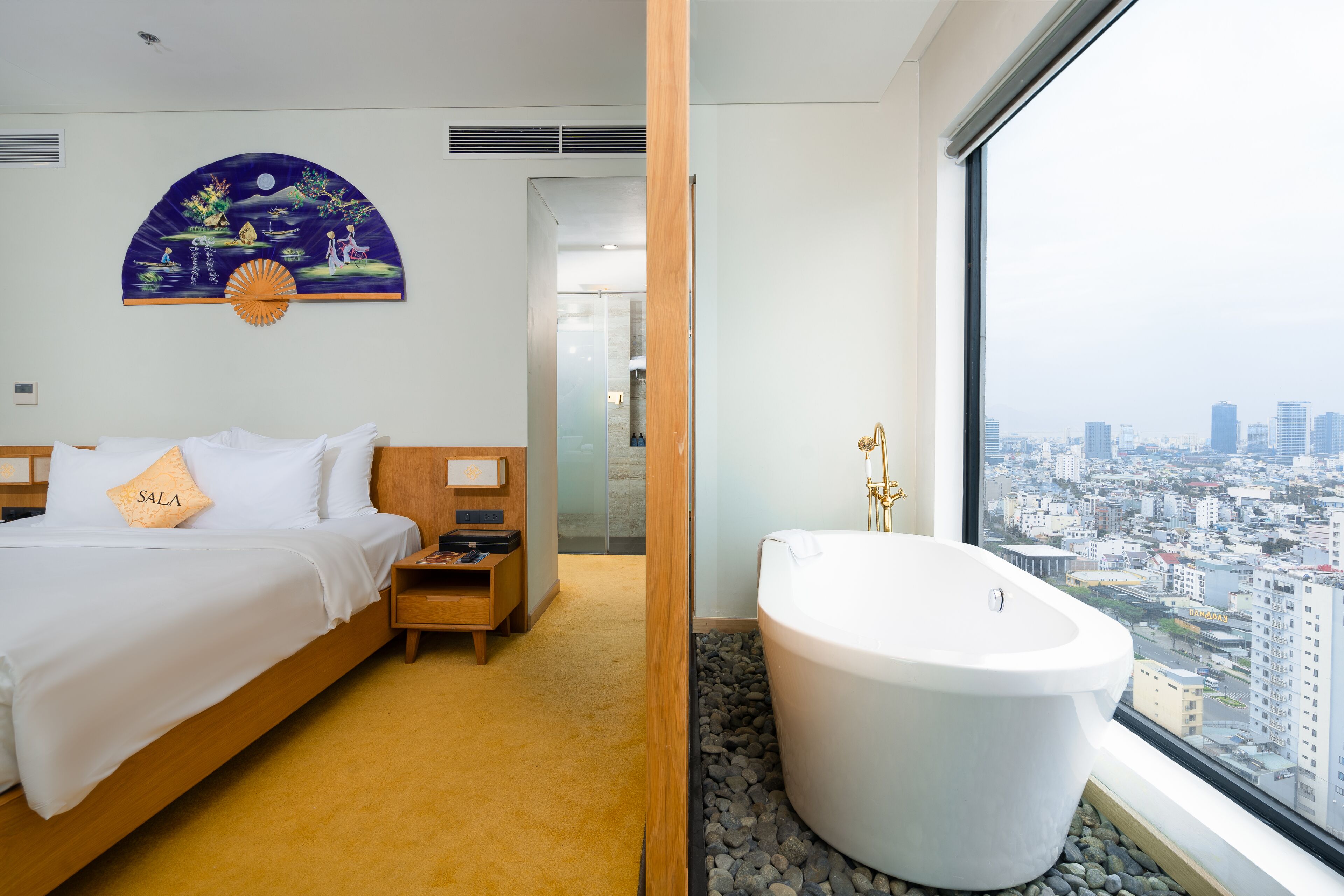 A hotel room with a bed, a bathroom with a bathtub, and a city view.