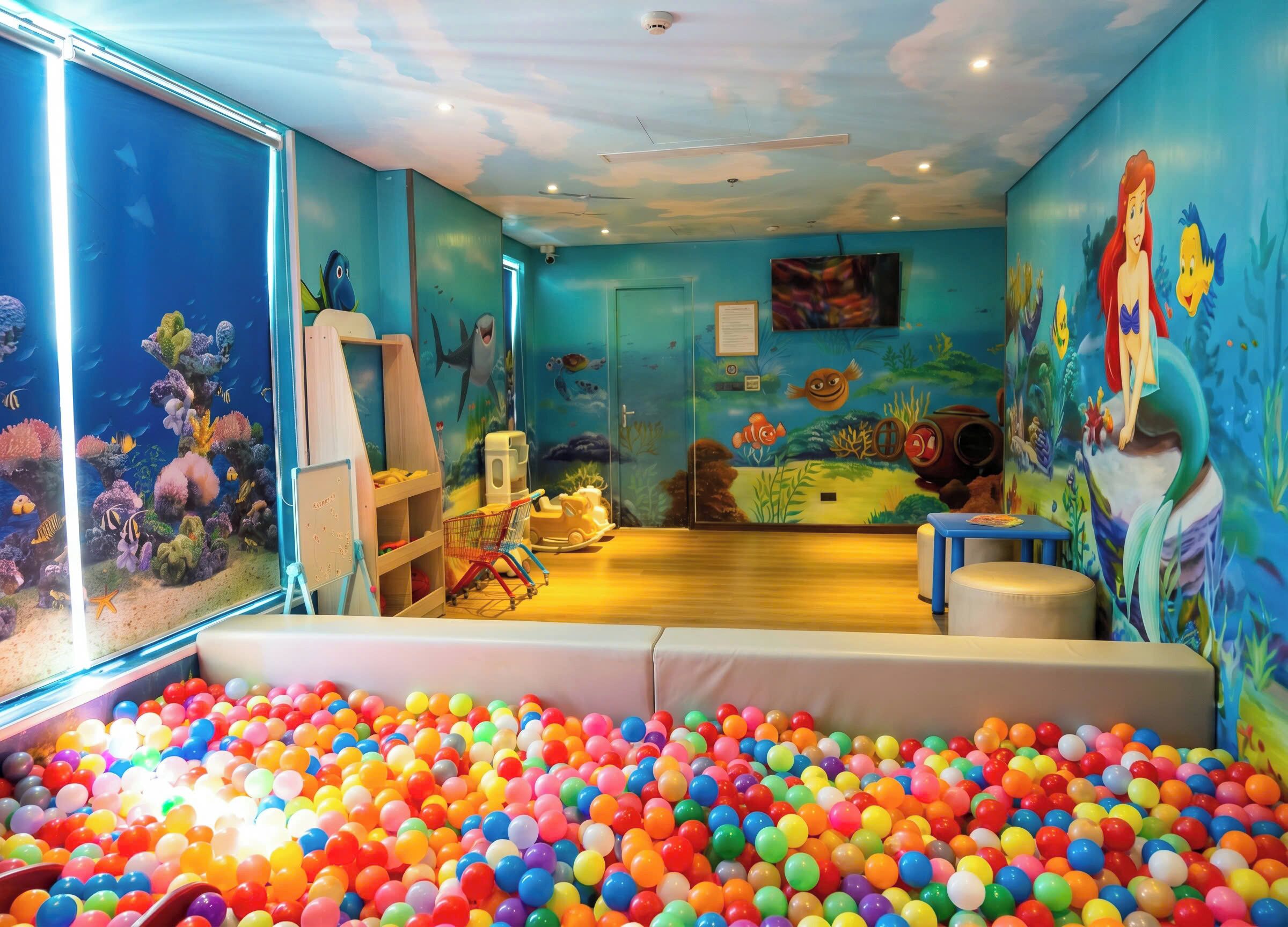 Une pièce avec un aquarium, une piscine à balles et une fresque représentant une sirène.