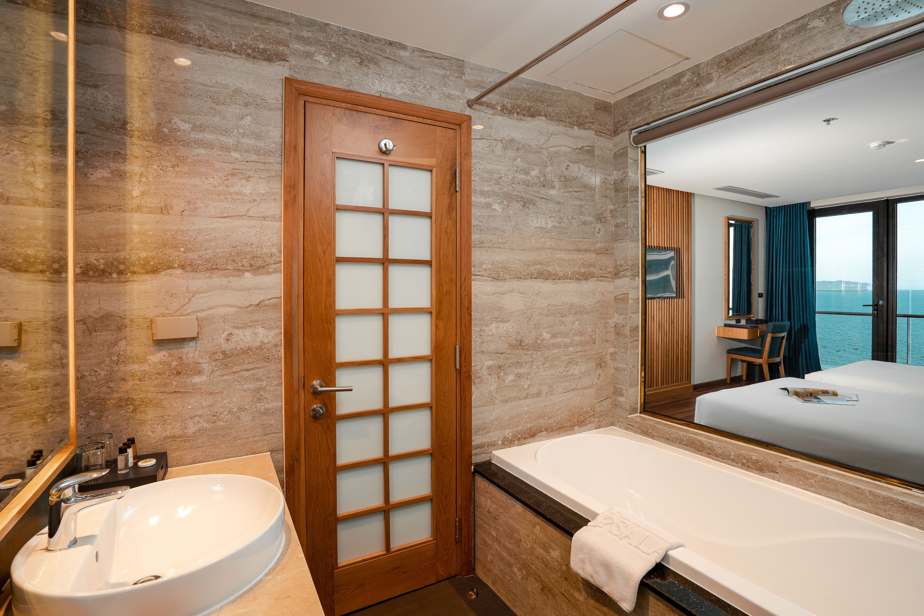 Un bagno moderno con un lavandino ampio, una vasca e una porta in legno con pannelli di vetro satinato.