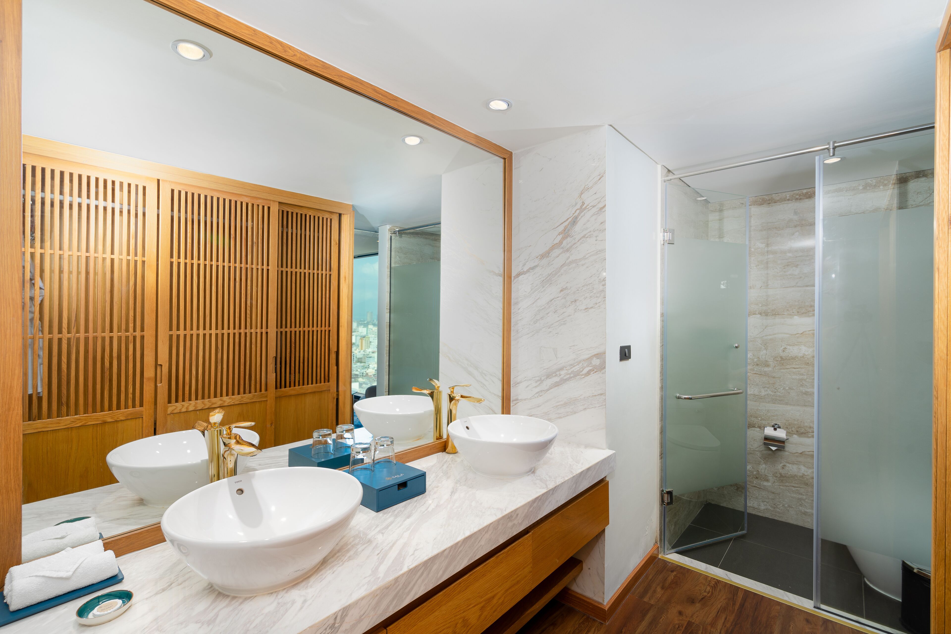 Une salle de bain moderne avec deux lavabos, un grand miroir et une douche à parois de verre.