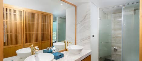 Une salle de bain moderne avec deux lavabos, un grand miroir et une douche à parois de verre.