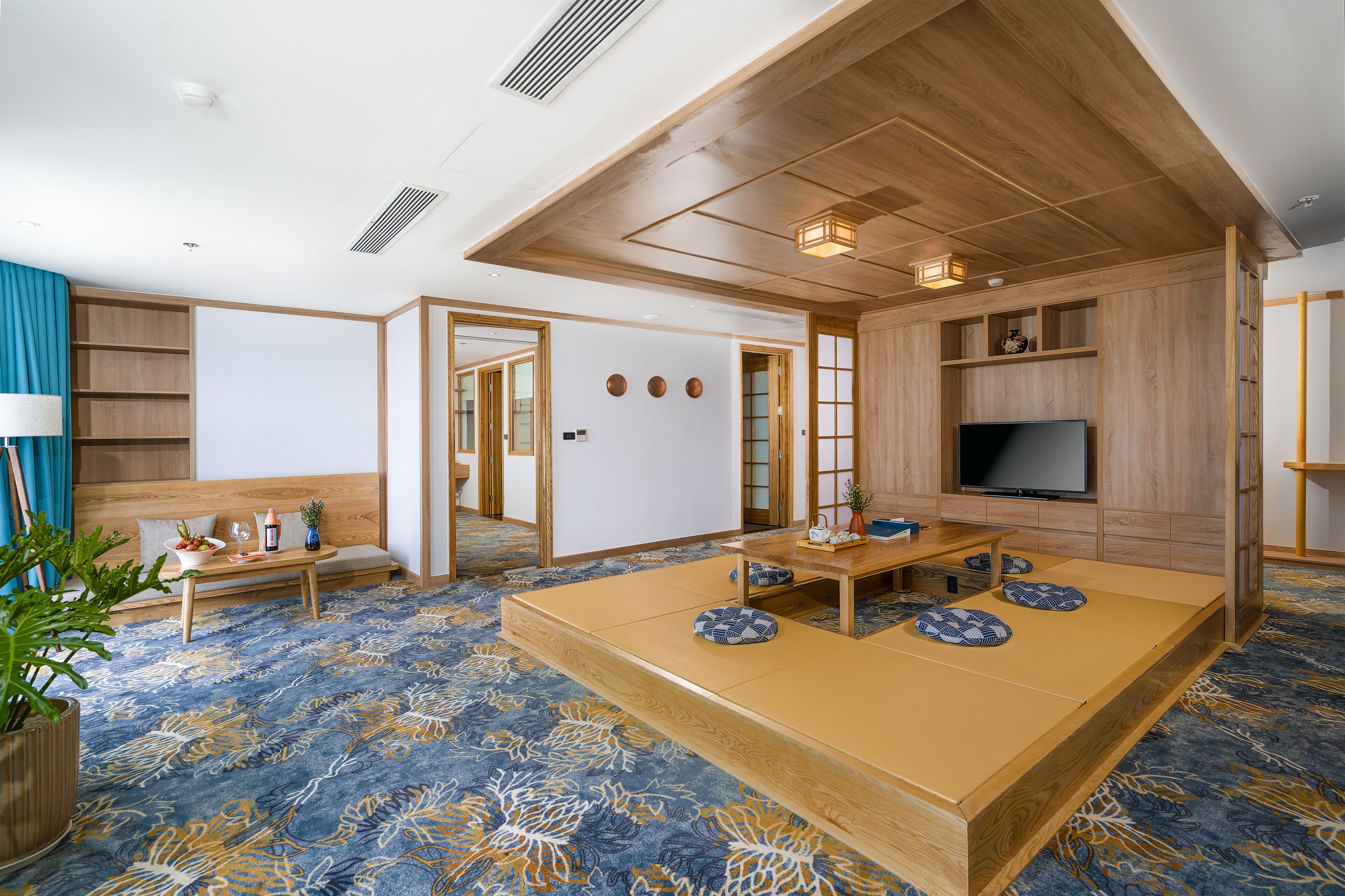 Une pièce de style japonais traditionnel, avec un sol recouvert de tatamis, une petite table en bois, un canapé et un téléviseur.