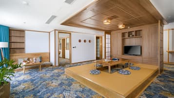Una habitación tradicional japonesa con suelo de tatami, una mesa de madera baja, un sofá y una televisión.