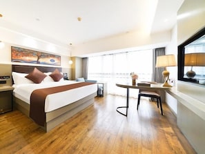 A hotel room with a large bed, a desk, and a window with curtains. - GYA Hotel Jin Ji Lake Oriental Gate (Suzhou)