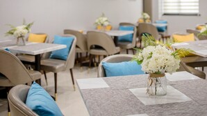 A dining area with tables set for guests, featuring floral centerpieces and blue cushions. - GYA Hotel Jin Ji Lake Oriental Gate (Suzhou)
