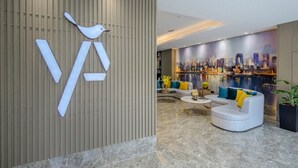 A modern lobby with a unique wall design, a seating area with a sofa and armchairs, and a cityscape mural in the background. - GYA Hotel Jin Ji Lake Oriental Gate (Suzhou)