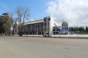 Un edificio moderno con amplias ventanas y techo plano, ubicado al lado de una carretera bajo un cielo despejado.
