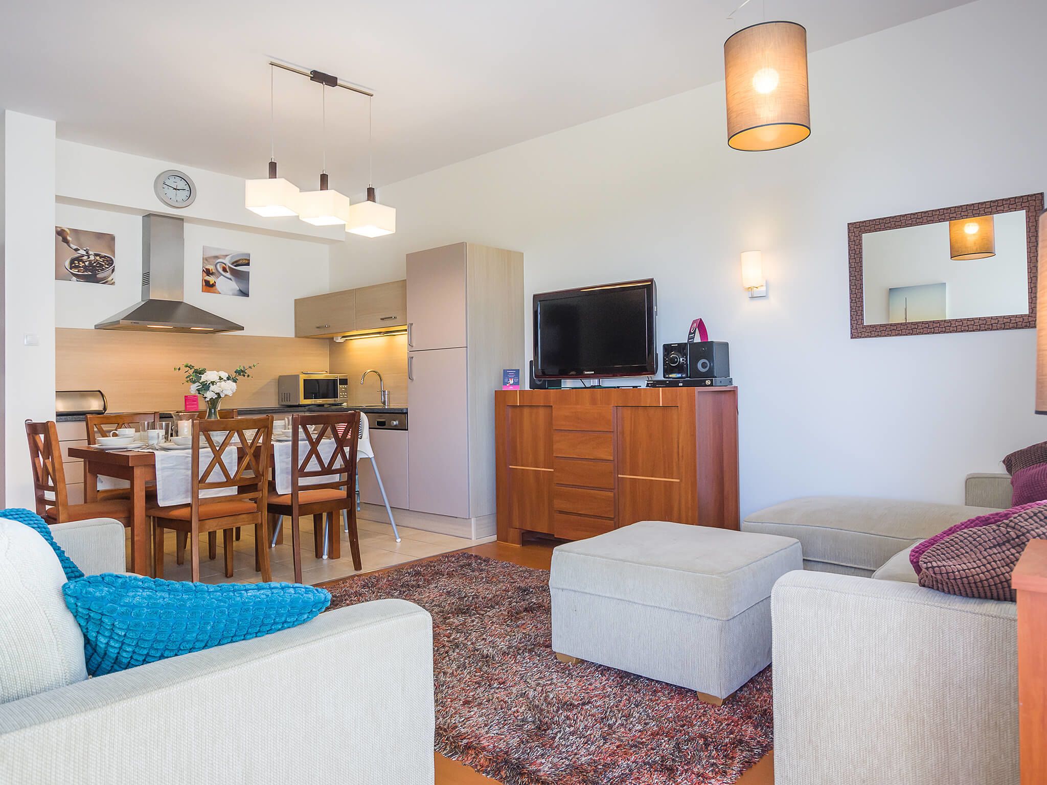 Un appartement moderne comprenant un coin repas, une kitchenette, un salon et un téléviseur.