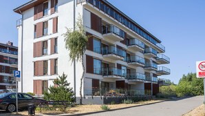 A multi-story residential building with balconies, a parking sign, and a no parking sign.