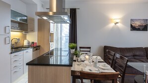 A modern kitchen with a central island, built-in appliances, and a dining area with a glass table and chairs.