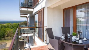 A balcony with a table set for dining, overlooking a scenic view.