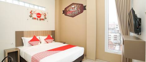 A hotel room with a bed, a nightstand, a TV, and a window with curtains.