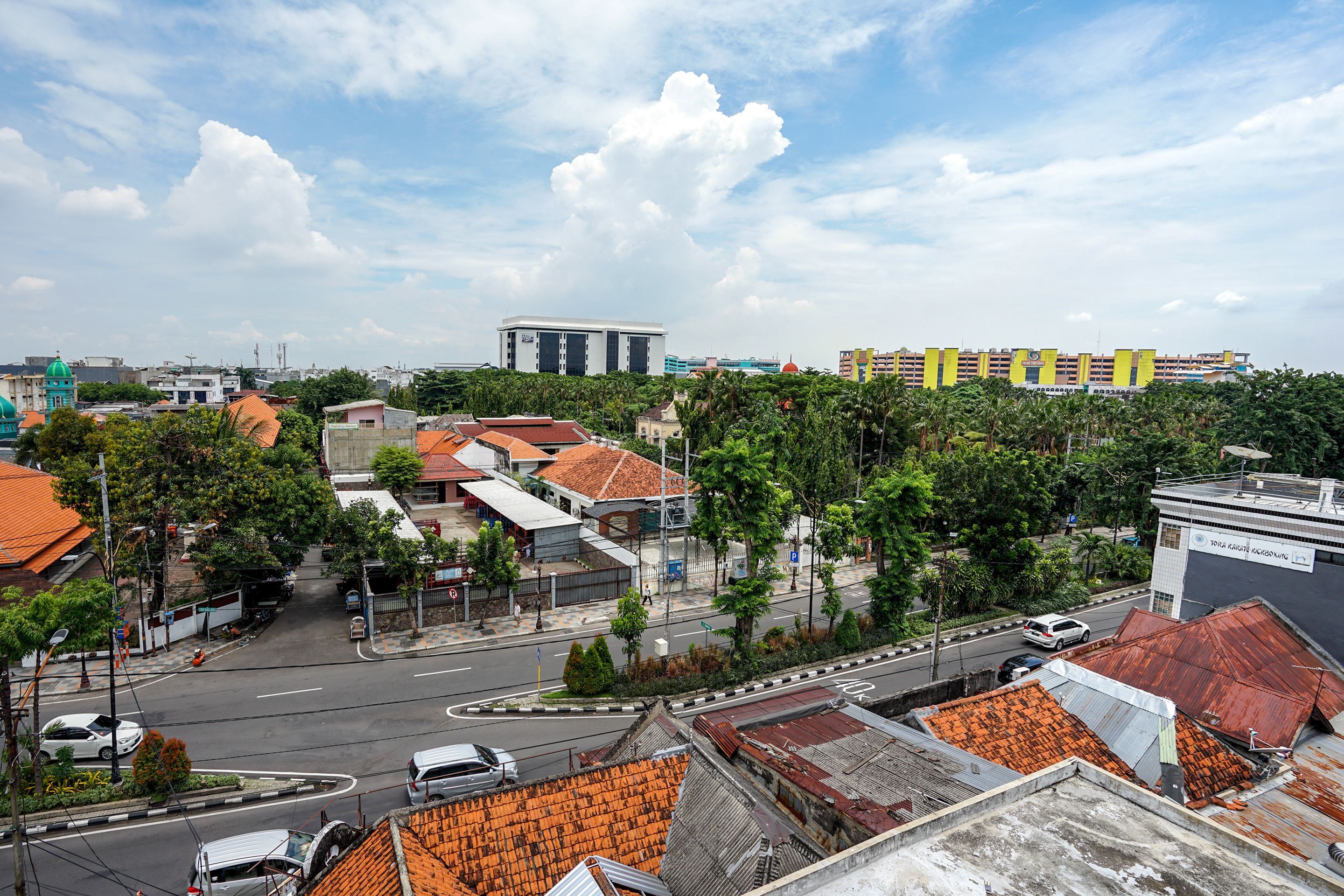 A cityscape with a mix of residential and commercial buildings, a prominent yellow building, and a road with vehicles.