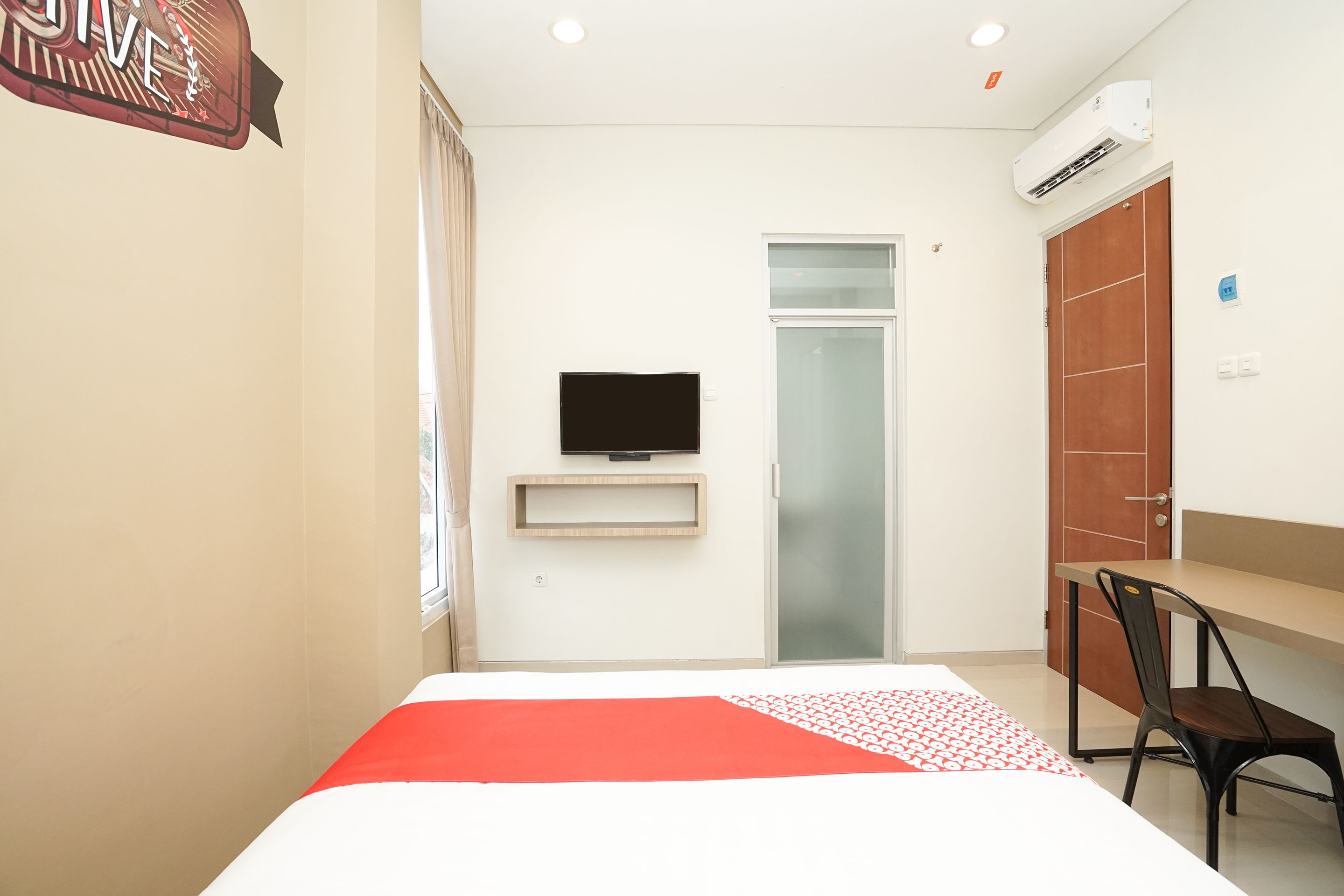 A hotel room with a bed, a desk, a chair, a television, and a wardrobe.
