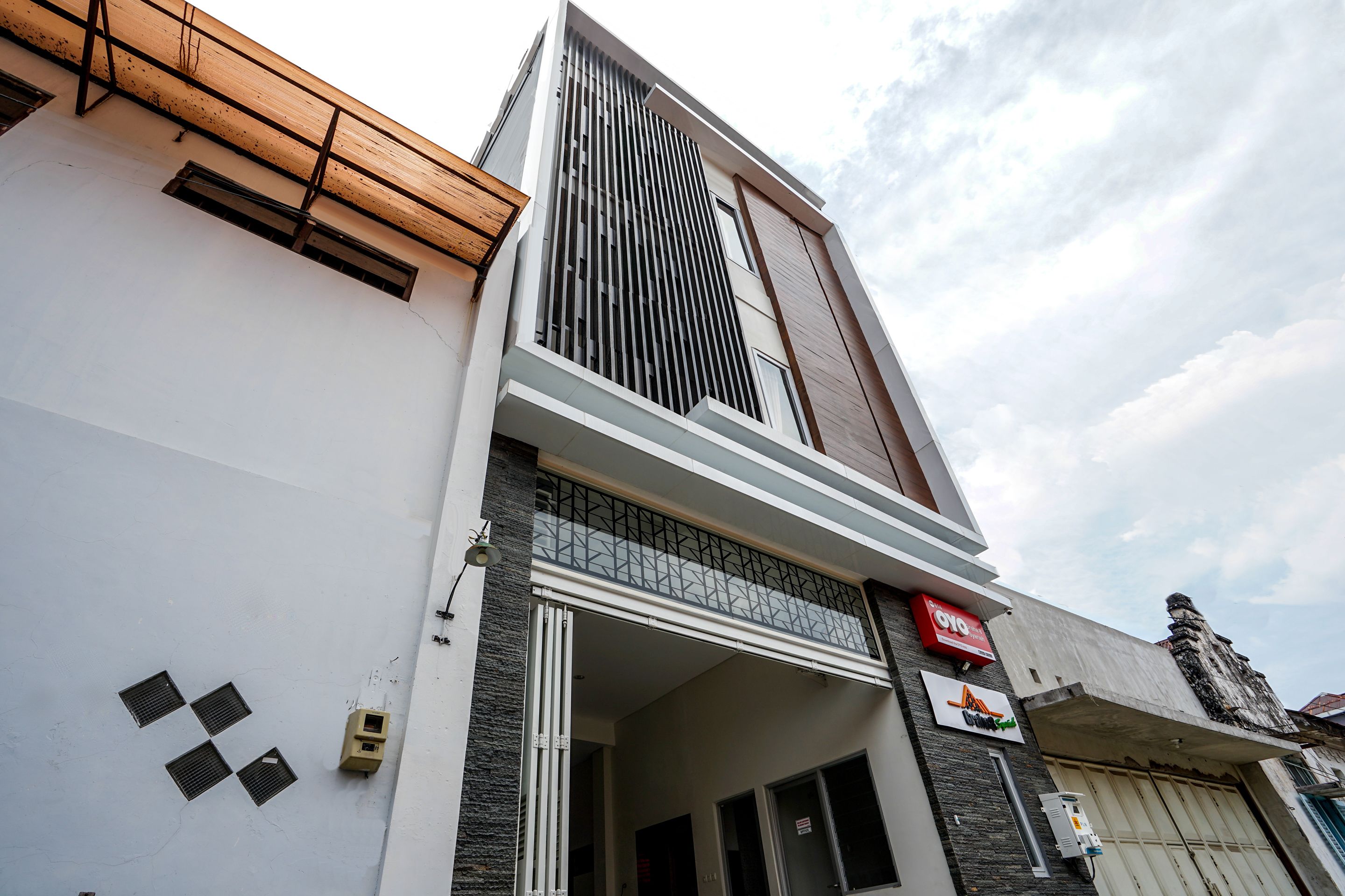A modern building with a large entrance, a visible staircase, and a sign indicating a business.