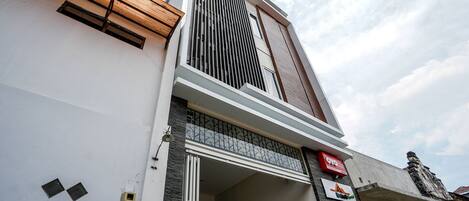 A modern building with a large entrance, a visible staircase, and a sign indicating a business.