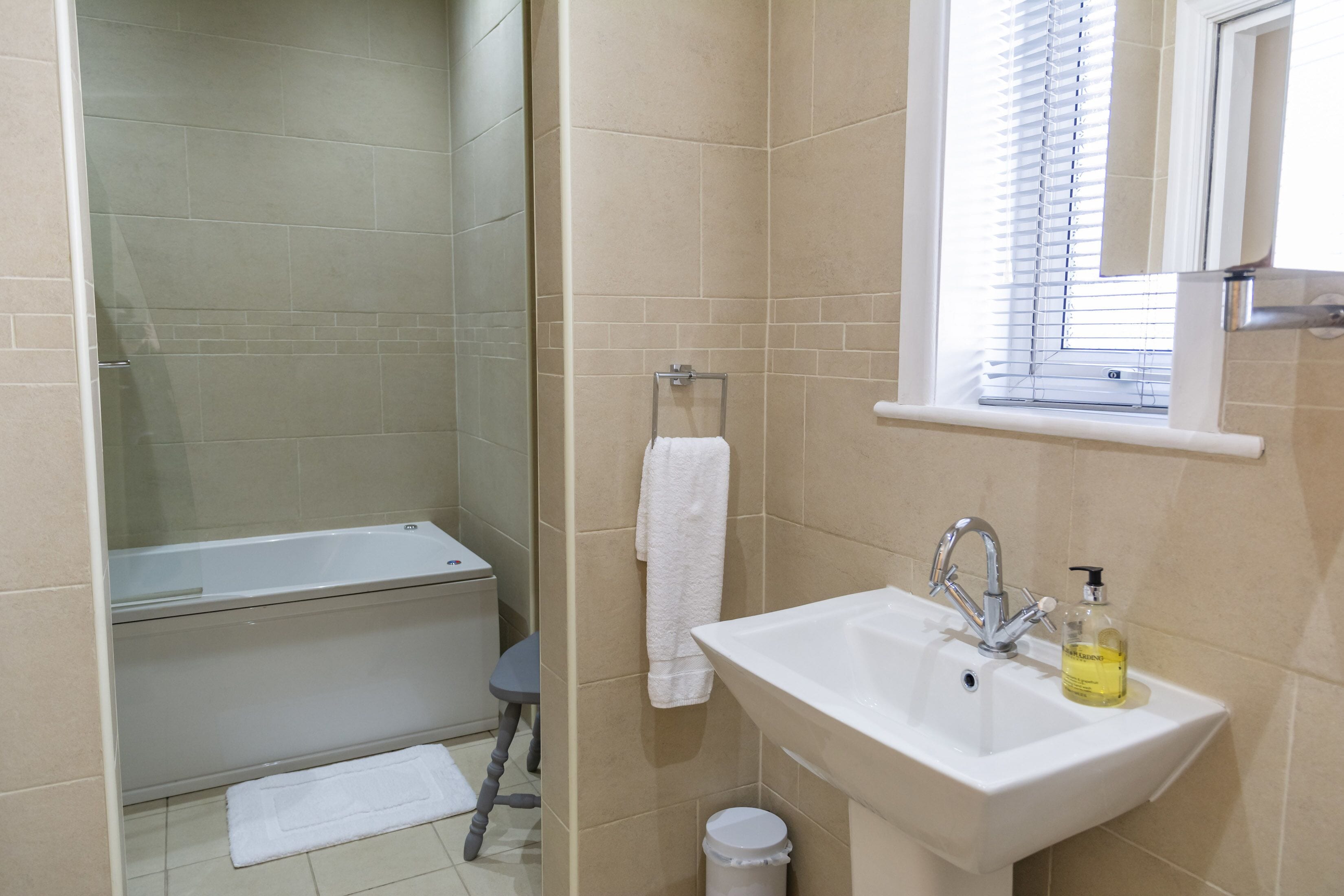 A bathroom with a bathtub, sink, and window.