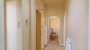 Un couloir étroit avec une porte en bois, une porte blanche et un radiateur sur le côté droit.