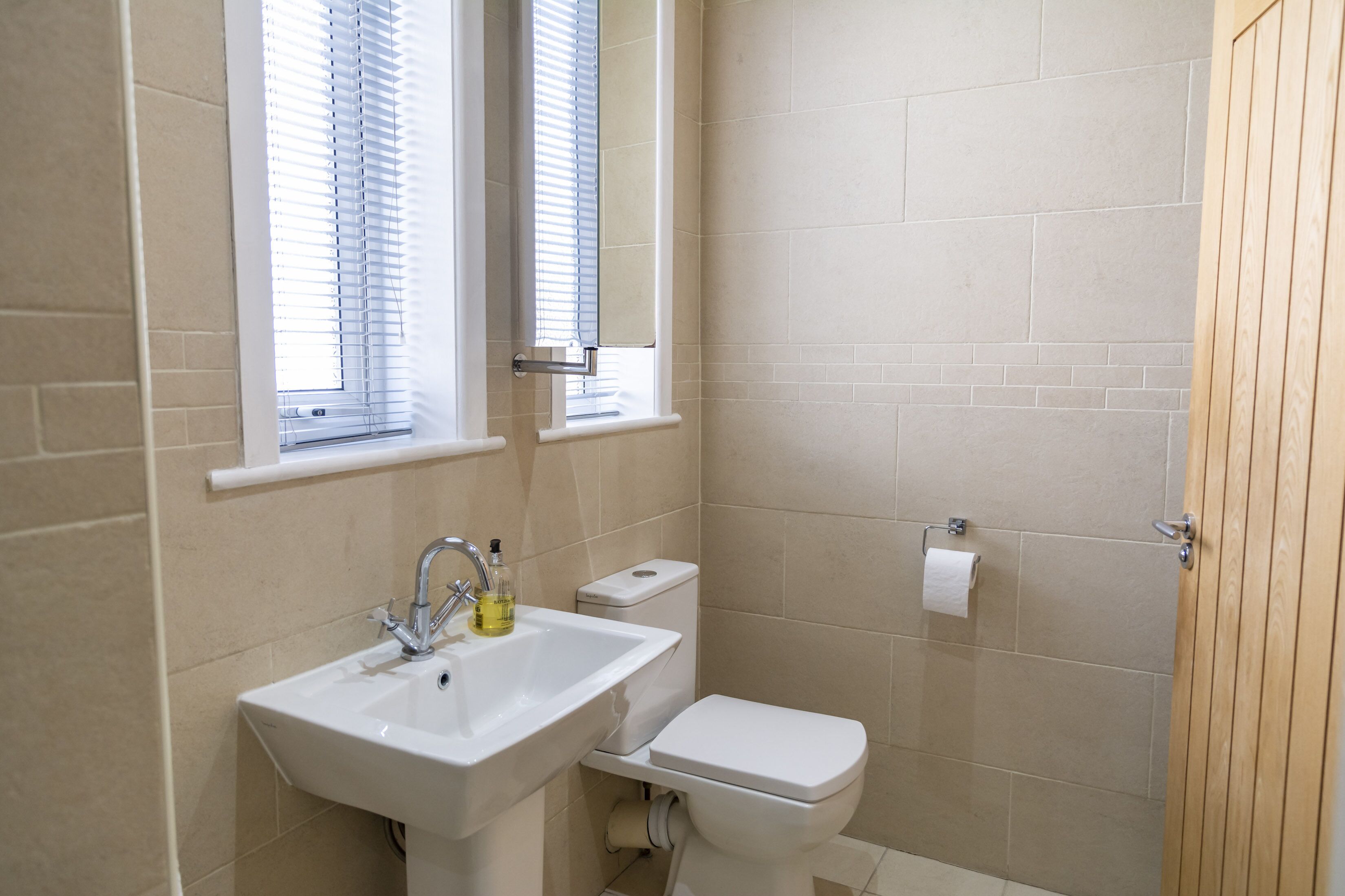 A bathroom with a sink, toilet, and window blinds.