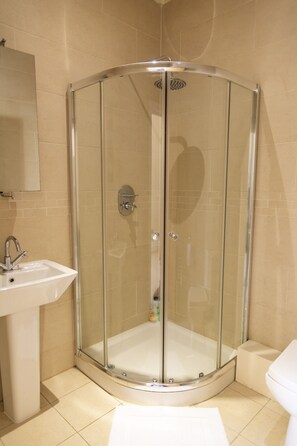A bathroom with a glass-enclosed shower, a sink, and a toilet. - Whitefield Charm Cozy 2 Bedroom Apartment Sleeps 8 (Manchester)