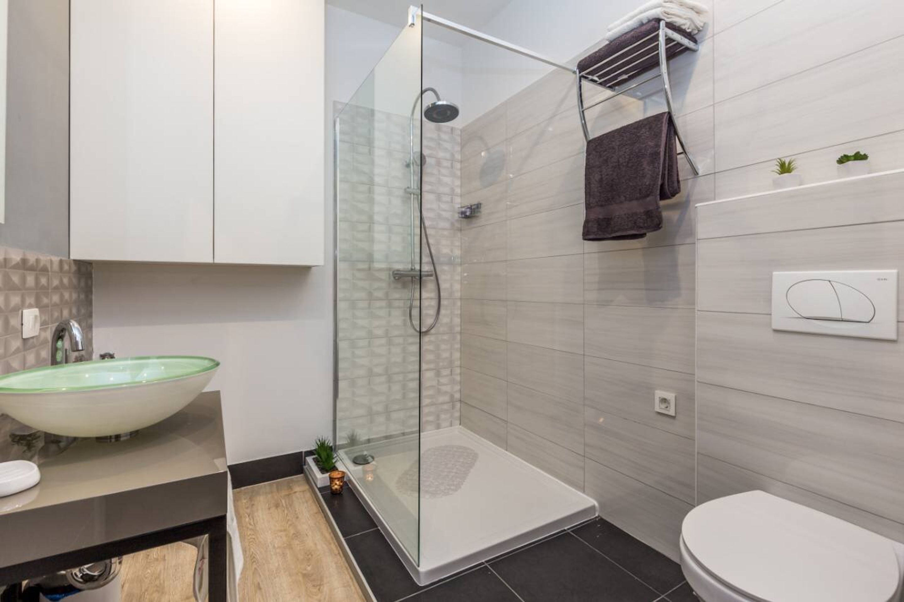 Une salle de bain moderne avec une douche à parois de verre, un lavabo blanc et des toilettes.