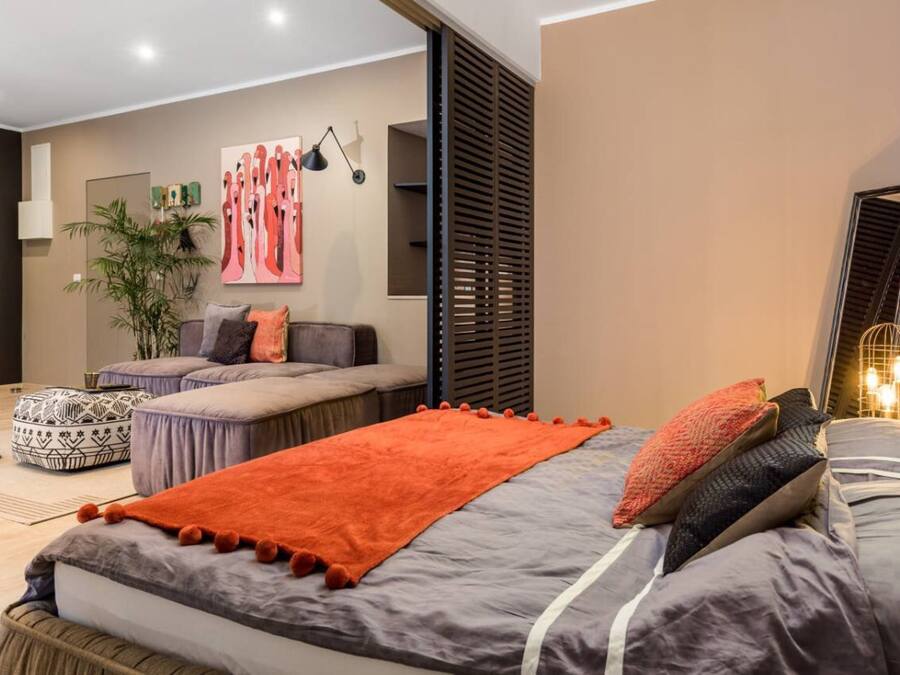 A modern bedroom with a large bed, a sofa, and a small table.
